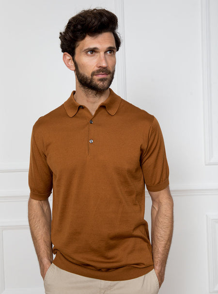 Man wearing ginger/burnt orange short sleeved polo sweater knit in 100% luxury and premium merino wool.